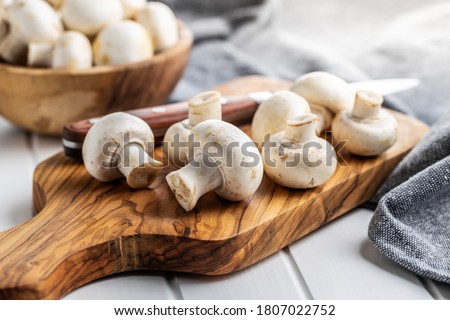 Fresh white champignon mushrooms on cutting board. Royalty-Free Stock Photo #1807022752