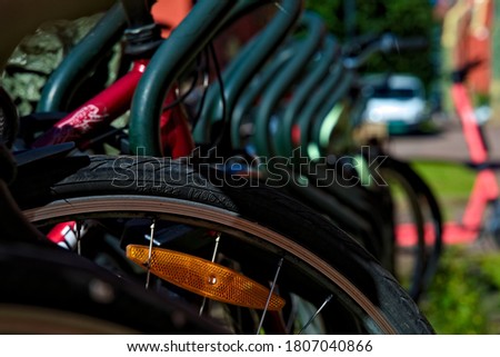 Bicycles parked in a row, in urban environment on a sunny day. focus on one wheel of a bike.
