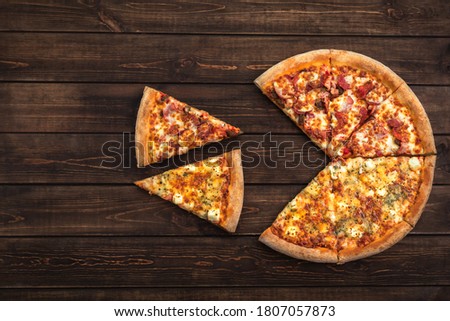 Pizza with two sliced pieces on a dark brown wooden background, copy space, top view, flat lay, fast food concept