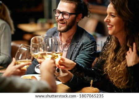 Group of friends in a restaurant, having diner and toasting with white wine. Royalty-Free Stock Photo #1807065235