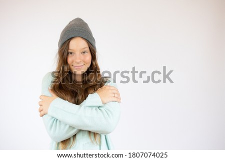 Smiling girl in winter clothes with the arms crossed