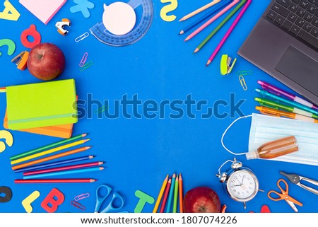 Back to school concept frame with school supplies on classic blue background