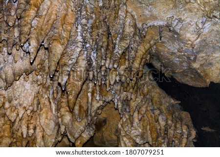 Internal images of caves, with geological formations of water dripping from the ceiling, forming stalactites and stalagmites formed on the floor. Geometric shapes and designs on the rock.