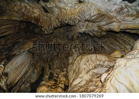 Internal images of caves, with geological formations of water dripping from the ceiling, forming stalactites and stalagmites formed on the floor. Geometric shapes and designs on the rock.