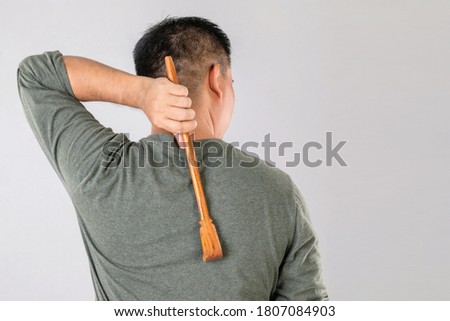Health care or Itchy or Tinea Cruris concept : Portrait of people using Scratching wood stick to Scratch on his back side. Studio shot on grey background Royalty-Free Stock Photo #1807084903