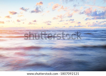 Epic colorful glowing pink sunset clouds above the sea after a thunderstorm. Dramatic sky. Waves and water splashes texture. Idyllic seascape. Concept image, long exposure. Picturesque scenery