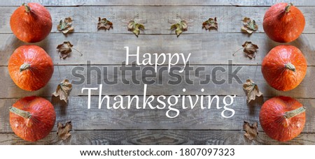 Happy Thanksgiving Day. Pumpkins and leaves on a wooden background. Happy Thanksgiving lettering. Banner