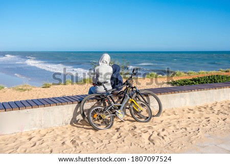 Back view of family looking at the beach, tourists use bicycles. Sunny blue sky outdoors background. Ecotourism activity concept