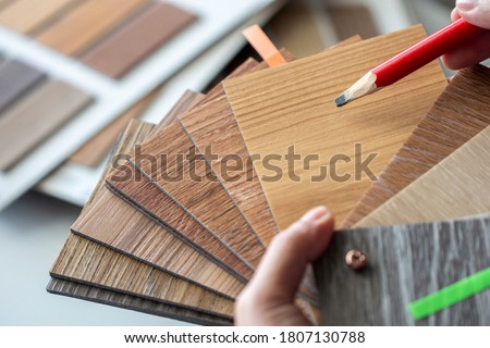 Interior designer hand holding sample stack of vinyl wood sheet to select floor tile material works Royalty-Free Stock Photo #1807130788