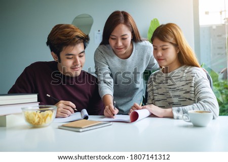 Group of young students tutoring and  catching up workbook with friends