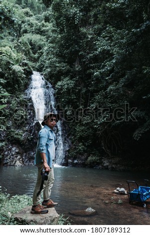 Travel photographer standing at the waterfall Thanthip Sangkhom, Nong Khai Thailand. 
