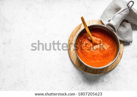 Homemade tomato sauce in cooking pan on white table, top view, copy space. Making organic italian tomato sauce or soup.