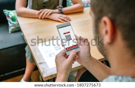 Unrecognizable man scanning restaurant menu QR code on table Royalty-Free Stock Photo #1807275673