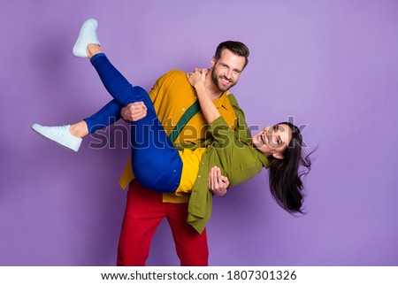 Photo charming lady handsome fiance guy couple carry wife bride hold arms playful wedding day swinging not afraid wear casual bright shirts pants outfit isolated purple color background Royalty-Free Stock Photo #1807301326