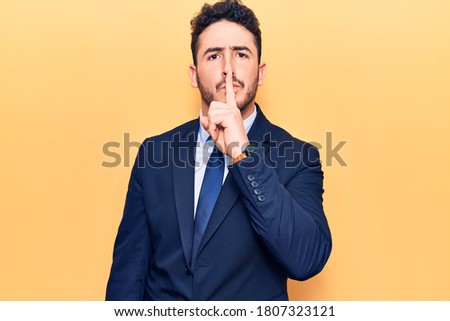 Young hispanic man wearing suit asking to be quiet with finger on lips. silence and secret concept. 