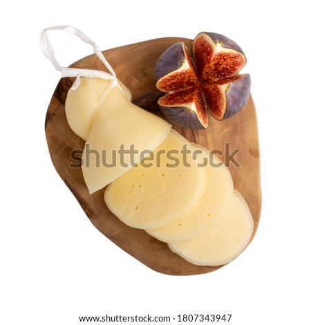 Cheese with figs on wooden board isolated on white. Cheese plate. Scamorza Italian semi-soft white cheese. Top view. Royalty-Free Stock Photo #1807343947