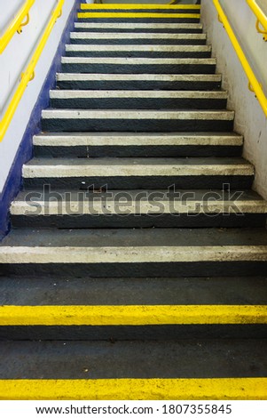 complete cement stair way painted with yellow and white steps and yellow hand rail