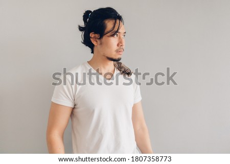 The Asian man in a white t-shirt stands with his pet on his holder.