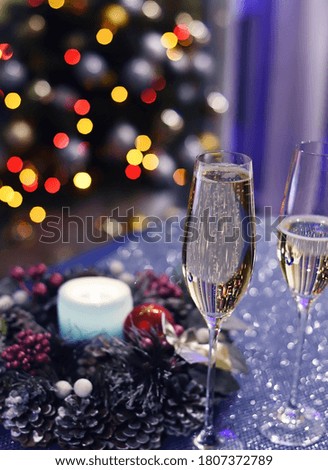 Two glasses of sparkling wine champagne, a Christmas wreath and the lights of the New Year tree in the background. home winter holiday atmosphere 