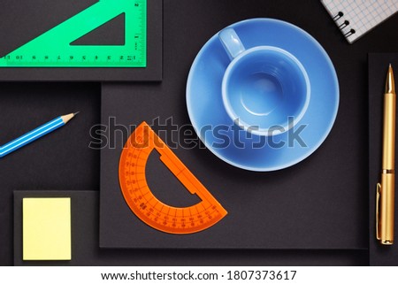 office supplies and empty cup of coffee at abstract black paper background