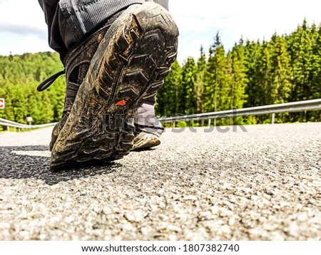 Close-up trekking shoes on mountain road with copy space. Outdoor activity. Healthy lifestyle. Tourist walks on a road. Trekking in mountains concept with hiking shoes.