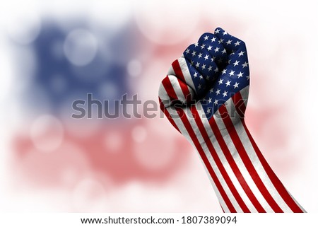 Flag of America painted on male fist, strength,power,concept of conflict. On a blurred background.