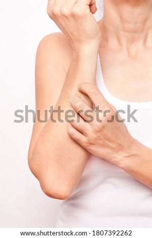 The woman is scratching her arm.