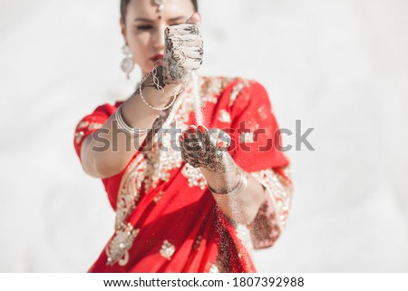 Indian woman pouring sand through her fingers. Bautiful female in sari outdoors