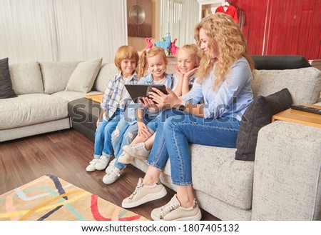 Happy family life at home. A mother spends time with her children using  PC tablet at home.