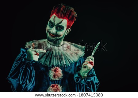 A portrait of an angry crazy clown with a knife from a horror film . Halloween, carnival.