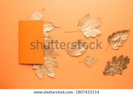 Blank card with gold leaves on orange. Autumn concept.