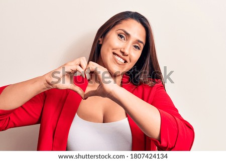 Young beautiful brunette woman wearing elegant jacket smiling in love doing heart symbol shape with hands. romantic concept. 