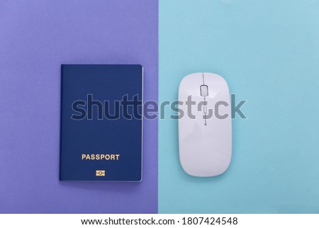 PC mouse with passport on a blue purple pastel background. Travel concept. Top view