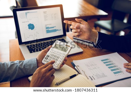 Managers are using tablets to analyze sales cost reports and explain summary reports to employees calculate and record summary information data in the office. Royalty-Free Stock Photo #1807436311