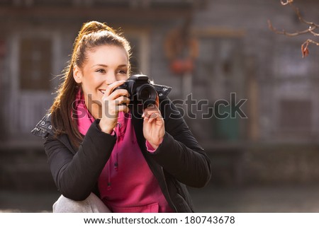 Young woman holding camera and taking photo outside