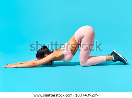 Sporty woman doing yoga cat pose and stretch exercise over blue background. fitness, training, healthy lifestyle