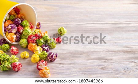 Colorful popcorn in yellow paper cup with text space