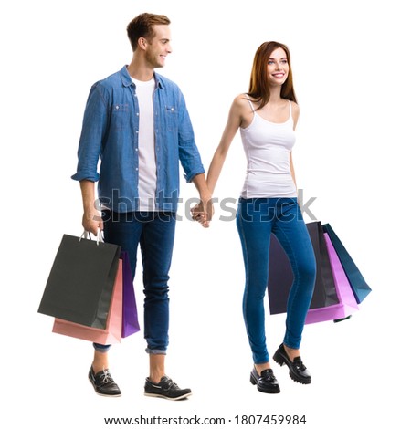 Holiday sales action, shop, consumer concept - couple with shopping bags, going for purchases, holding hands. Isolated over white background. Full body length studio ad portrait. Square composition. 