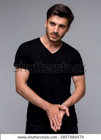 Hipster handsome male model with beard wearing black blank t-shirt with space for your logo or design in casual urban style