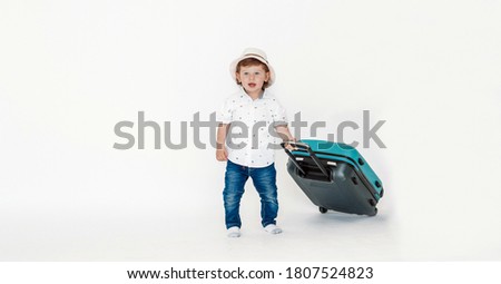 little boy carries a suitcase, isolated on white background. Tourism and summer vacation concept. Place for your text.