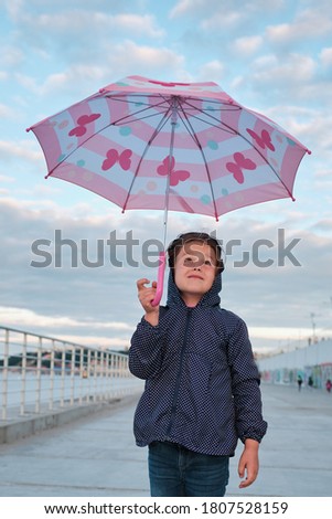 a girl stands under an umbrella waiting for a change in the weather