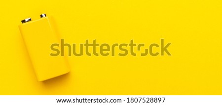 Blank nine-volt battery on the yellow background with copy space. Top view of yellow nine-volt battery. minimalist photo of blank battery.