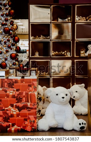 Decoraion of store window with white teddy bear toys and many red gift boxes and christmas tree on background. Merry Christmas and Happy New Year Holiday shopping concept