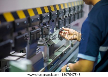 The operation of hydraulic bending machine with technician.  The  sheet metal manufacturing process by press brake bending machine with technician operator. Royalty-Free Stock Photo #1807547548