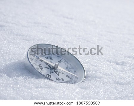 Round modern compass on the white snow, space for text. Concept for travelling and active lifestyle