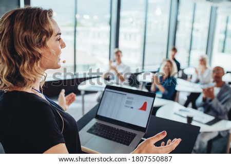 Businesswoman talking to business people from a podium. Female executive addressing to group of professionals at a conference.