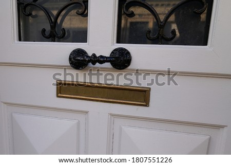 Shiny copper mailbox and black door handle metal on white old-fashioned wooden door in classic design close-up