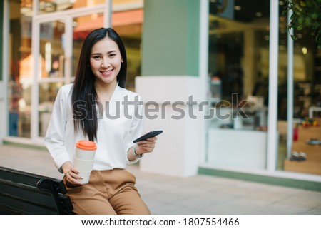 Woman sitting and using a smart phone in the street in a sunny summer day