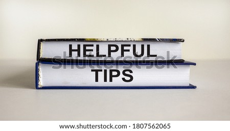 Books with text 'helpful tips' on beautiful white table. White background. Business concept. Copy space.