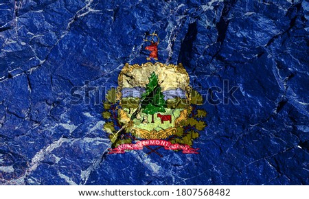 The national flag of the US State of Vermont on a blue background with the coat of arms in the center painted on the mountain wall for Independence Day. Rock graffiti of climbers during the ascent.